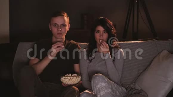年轻夫妇在家看电视上的恐怖对尖叫者的反应视频的预览图