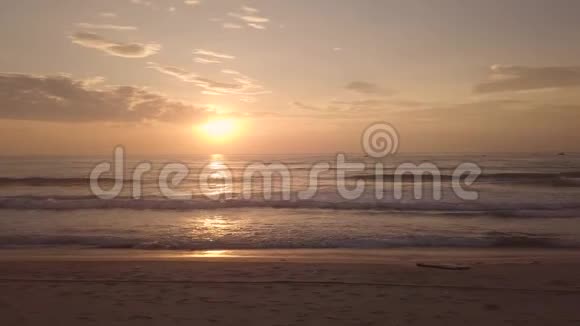 清晨日出在天空中的夏季海滩鸟瞰人们在沙滩上金色的天空中看着晨曦视频的预览图