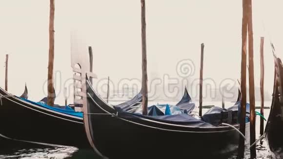 在意大利威尼斯的雾蒙蒙的木制泻湖码头美丽的传统贡多拉斯在波浪上摇摆的大气景观视频的预览图