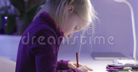 晚上一个可爱的女学生在一张白色的桌子上用铅笔画画视频的预览图