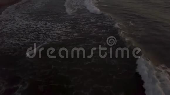 清晨日出时无人机在沙滩上飞过海水波浪从水面上的空中景观视频的预览图