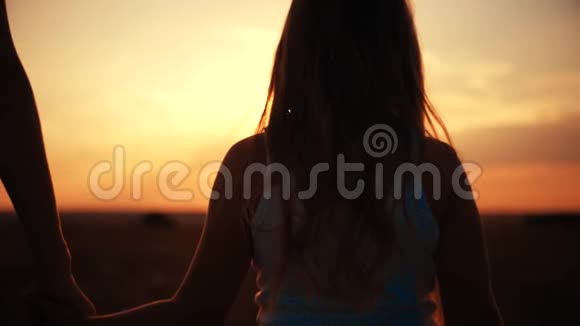 母亲和女儿日落背景的剪影彩色天空背景橙色和金色夕阳视频的预览图