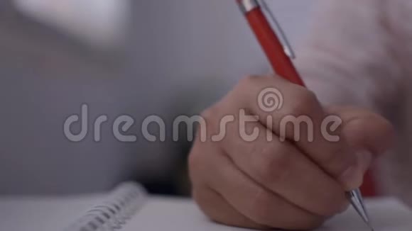 女人的手写在记事本上打字键盘在办公桌上视频的预览图