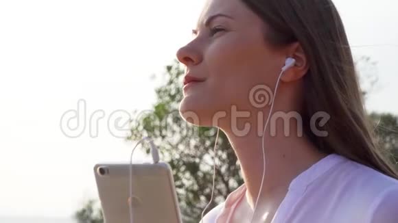 绿色公园里的女人女性通过手机慢动作听音乐然后唱歌视频的预览图