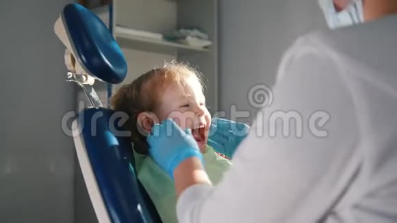 在牙科医生接待的女孩口腔医生给孩子清洗和浇水牙齿女孩微笑着说话视频的预览图