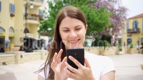 动作缓慢女人在欧洲城市的街上走着用手机浏览和朋友聊天视频的预览图