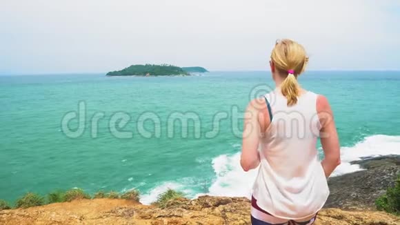 有岩石和波浪的海岸旅游和旅游女孩站在海边望着地平线视频的预览图