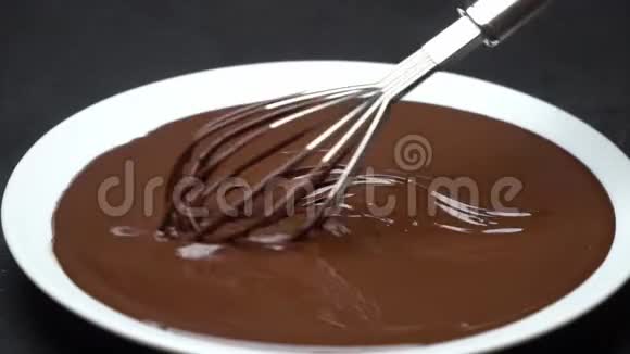 融化的牛奶或黑巧克力在盘子中旋转在混凝土背景上搅拌视频的预览图