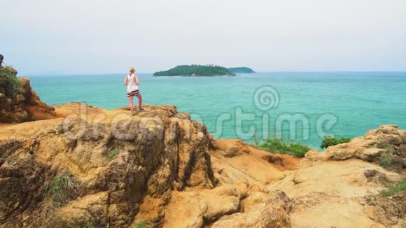 女人站在热带海洋的岸边眺望远方在热带岛屿上旅行视频的预览图