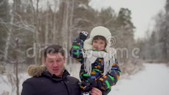 迷人的家庭在雪地冬季公园玩得很开心可爱的小男孩扔雪球父子俩在外面玩视频的预览图