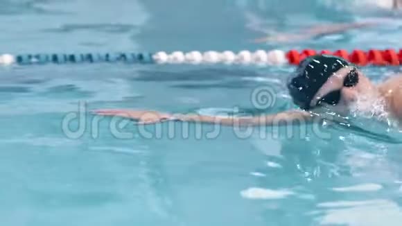 男子游泳运动员戴帽和护目镜在游泳池游泳的肖像视频的预览图