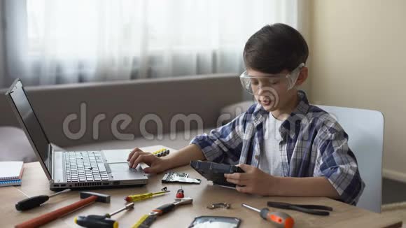 好奇的男孩戴着安全眼镜在笔记本电脑上搜索HDD指令爱好视频的预览图