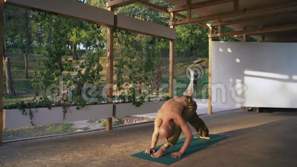 光着脚裸着躯干的年轻人在城市公园的木制Pomo上表演瑜伽体式视频的预览图