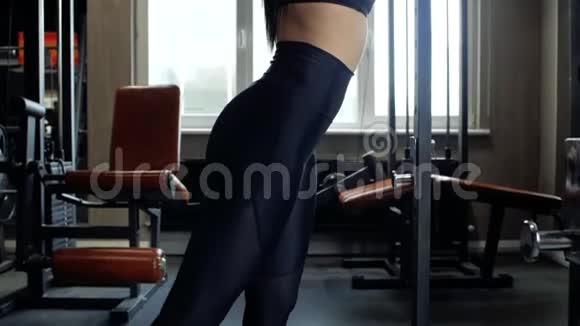 美丽的黑发女孩穿着黑色紧身裤在健身房做热身运动年轻女孩伸展身体视频的预览图