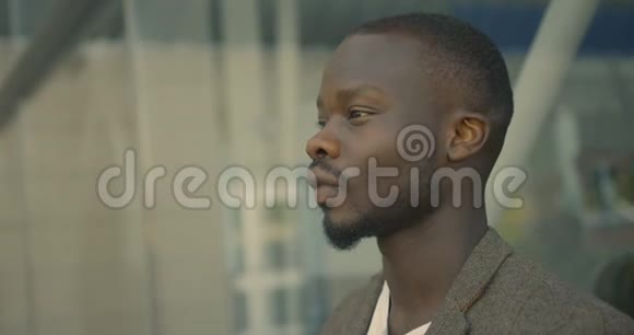 一个穿西装的严肃时髦的非洲男人在街上戴上太阳镜的4K镜头视频的预览图