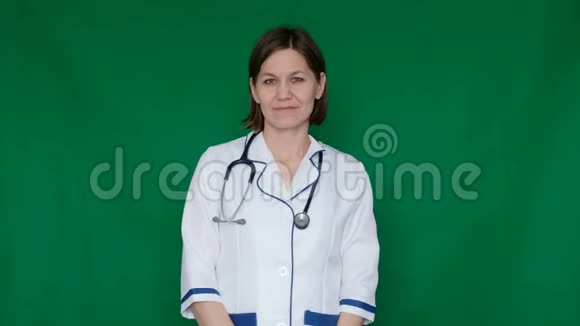 微笑自信的女医生穿着实验室外套看着绿色屏幕上的相机Chroma键视频的预览图