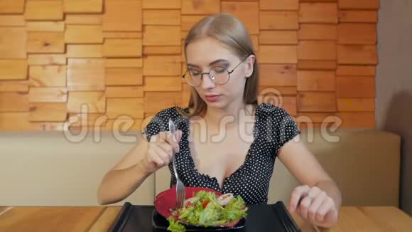 坐在餐桌前敞开领口的小女孩吃沙拉视频的预览图