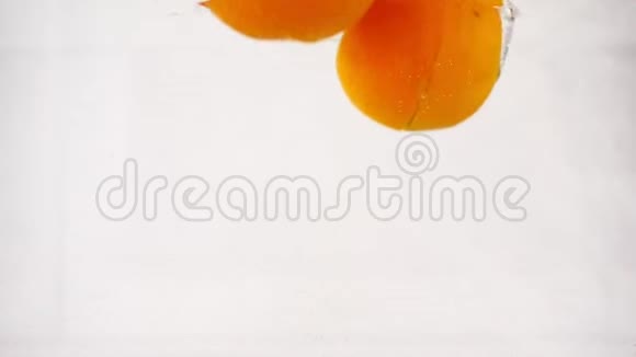 溅出的橘子在水中迅速下沉气泡慢动作特写视频的预览图