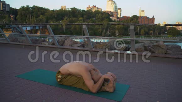 年轻的秃头Yogi在早晨的城市背景下在城市公园训练前锻炼视频的预览图