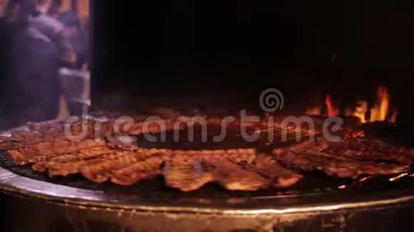 肉在一个大烤架里煎在巨大的旋转网格上烤火的排骨视频的预览图