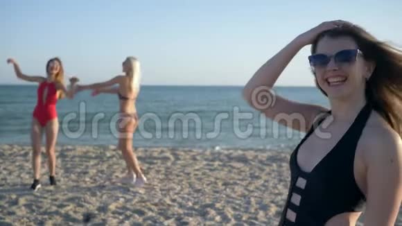 海滩上朋友背景下戴眼镜穿泳衣的欢快女性肖像视频的预览图