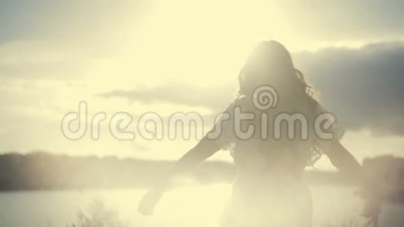 一个穿着白色裙子的欧洲女孩站着向阳光挥手一个年轻的女人穿着白色的裙子视频的预览图