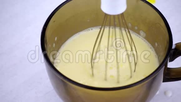 电动搅拌器把牛奶和鸡蛋打在玻璃碗里慢动作烹调小鼓视频的预览图