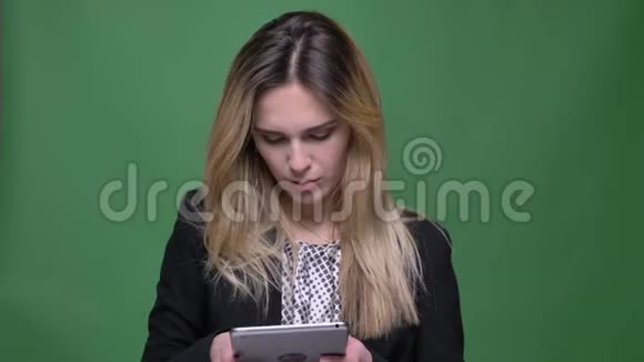 年轻迷人的红种人白种人女性特写镜头使用的平板电脑背景与绿色隔离视频的预览图