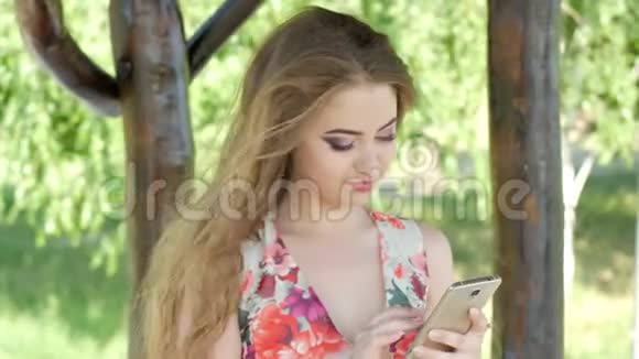 夏天公园里一位轻松的年轻女士在手机上读短信的肖像视频的预览图