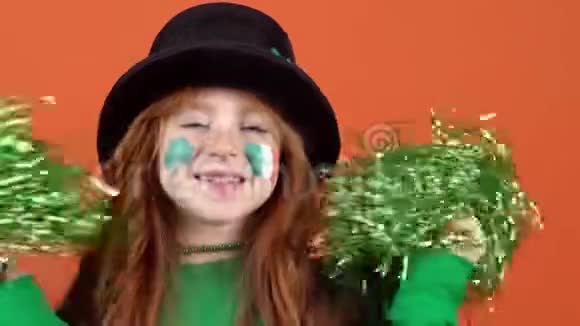 女孩红发庆祝圣帕特里克日橙色背景持有pomp视频的预览图