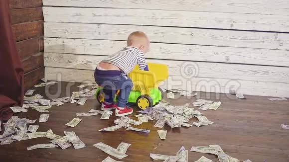 这个男孩在地板上玩玩具车那里有很多钱财富概念视频的预览图