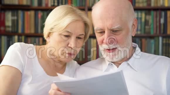老年夫妇阅读投资理财文件有税务报告的退休养恤金领取者家庭视频的预览图
