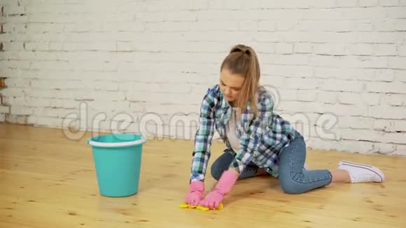 震惊的女人用很多工具打扫房子年轻疲惫的女孩在桶里扔一块抹布视频的预览图