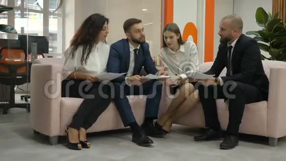 办公室工作人员两个年轻男子和两个年轻妇女坐在沙发上讨论公司的重要文件一个是视频的预览图