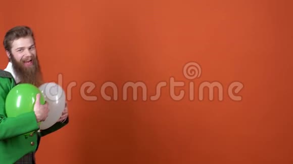 年轻的妖精庆祝圣帕特里克日子隔离在橙色的墙上手里拿着气球视频的预览图