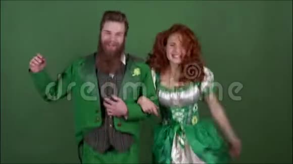 穿着盛装庆祝圣帕特里克节的年轻夫妇绿墙隔离在一起跳舞视频的预览图