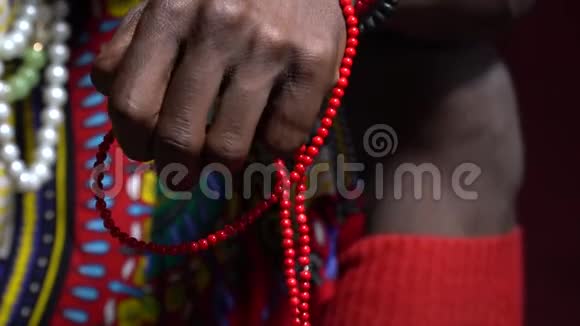 一名身穿国服的安哥拉黑人男子正拿着珠子坐在红色的背景上视频的预览图