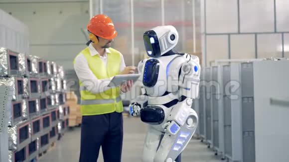 工厂的男员工向机器人解释并调节机器人的设置视频的预览图
