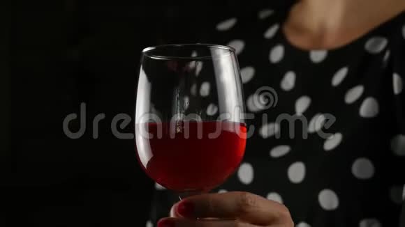 美丽的年轻女子在黑暗中喝红酒带着一杯酒的美女4K视频的预览图