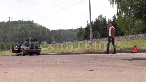 一个年轻人在一辆破车附近打电话视频的预览图