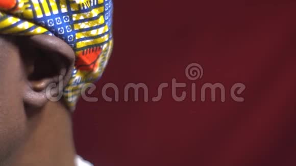 一个来自安哥拉的黑人男性穿着传统的头饰把脸转向相机闭上眼睛视频的预览图