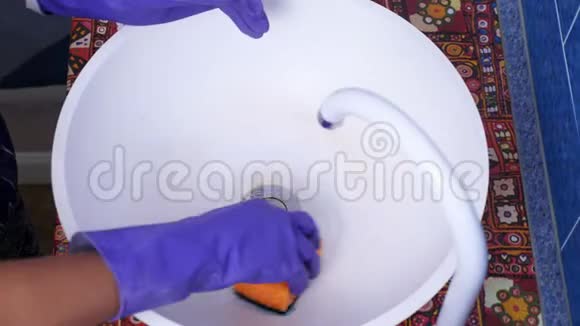 特写女手戴紫色防护手套清洗水槽用清洁剂清洗陶瓷圆脏水槽视频的预览图