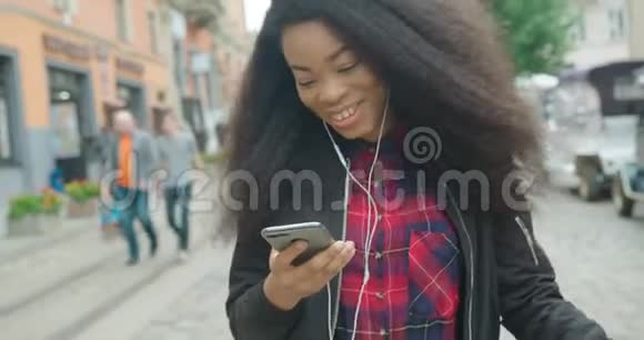 快乐迷人的非洲女孩带着美丽的微笑聊天发短信上网边听音乐边跳舞视频的预览图