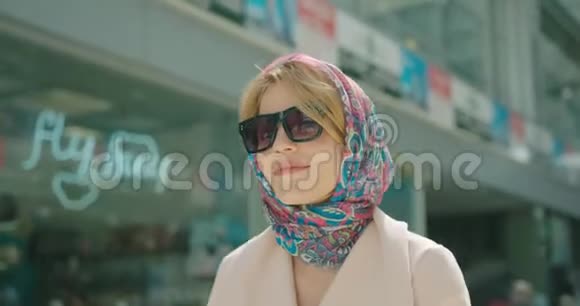 漂亮的时髦女郎戴着太阳镜戴着围巾金发碧眼走在现代购物中心视频的预览图