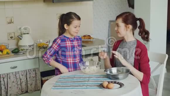 小有趣的女孩在厨房里帮助她的母亲把鸡蛋切成碗并把面团混合成饼干家庭食物视频的预览图