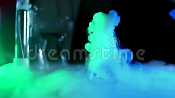 带有彩色液体的面罩在霓虹灯下蒸着与水中的干冰进行漂亮的化学反应的概念视频的预览图