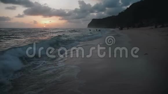 海浪和迷人的热带海滩与美丽的山脉在巴厘岛日落视频的预览图