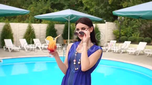 女孩站在泳池边摘下太阳镜视频的预览图
