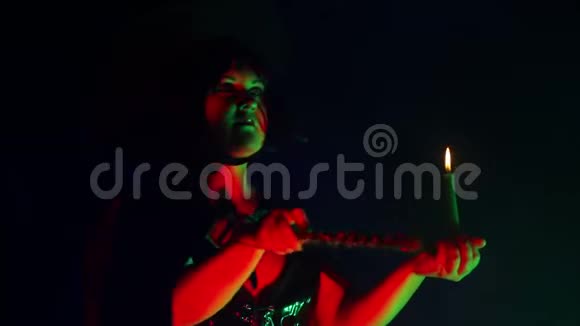 一个年轻的女巫的脸在一个烟雾中手里拿着蜡烛用魔杖处理魔法视频的预览图