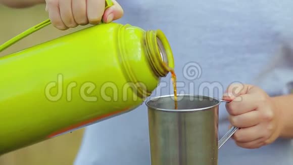 女人的手把热水瓶里的热茶倒进杯子里视频的预览图